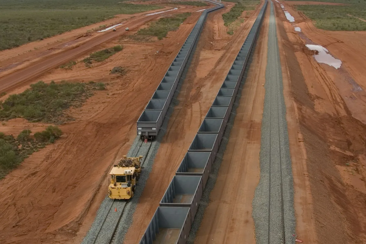 An iron ore train running across red earth near Port Hedland, Western Australia